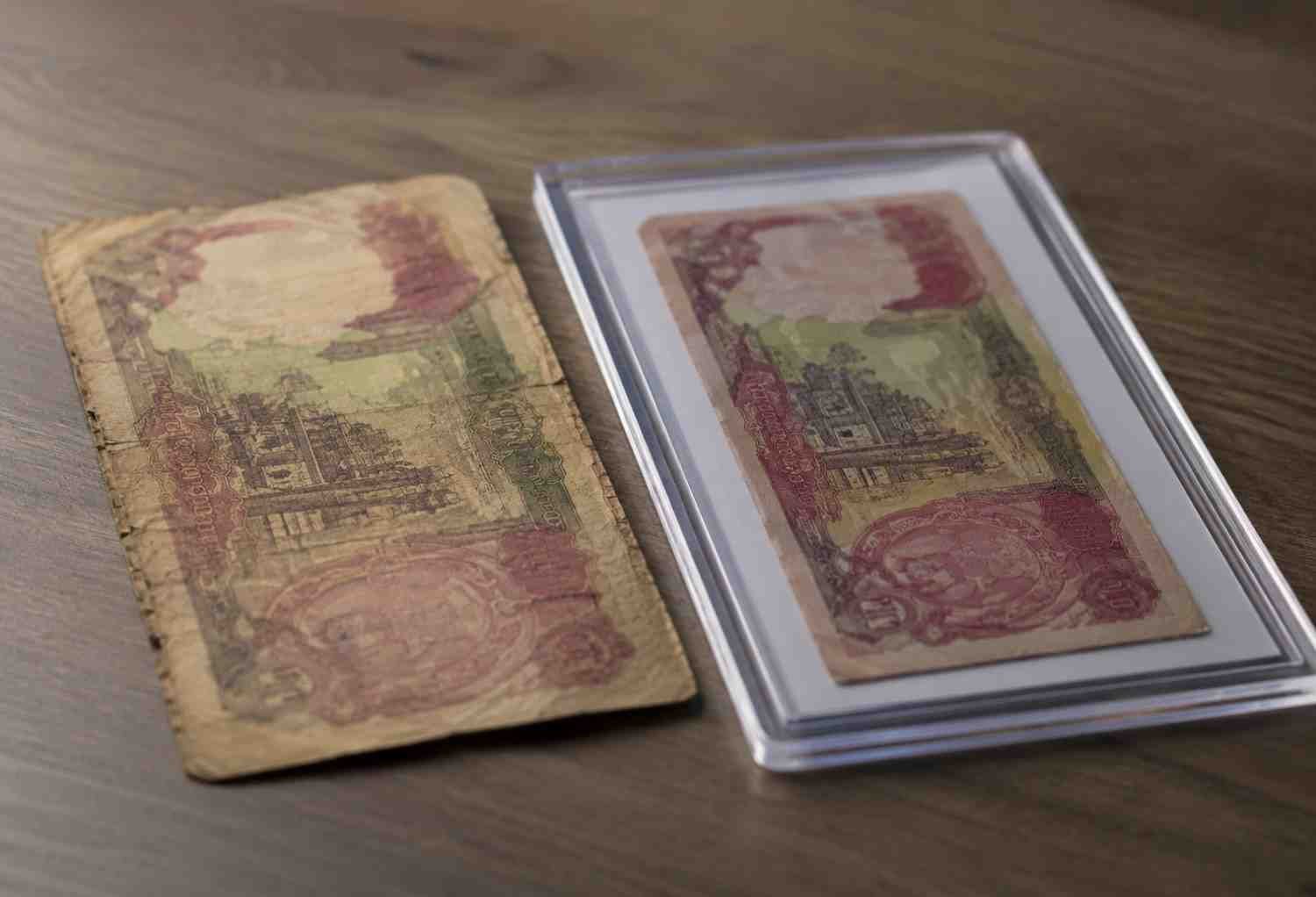 worn circulated banknote next to authenticated Iraqi Dinar notes in a protective holder, buy Iraqi Dinar online